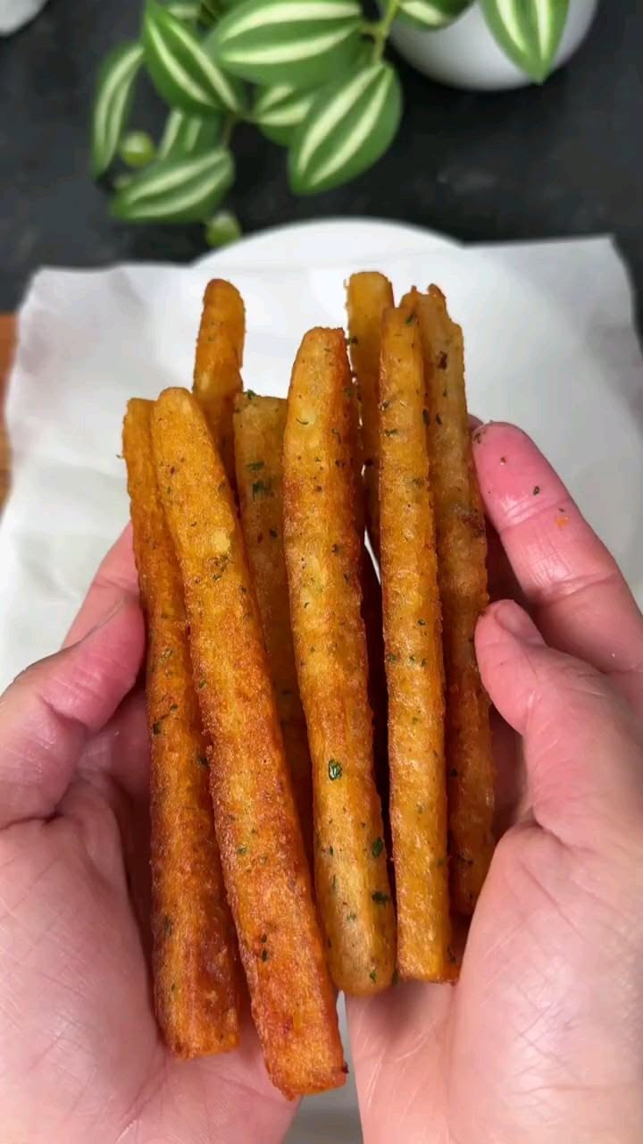 Hand holding thick seasoned potato fries